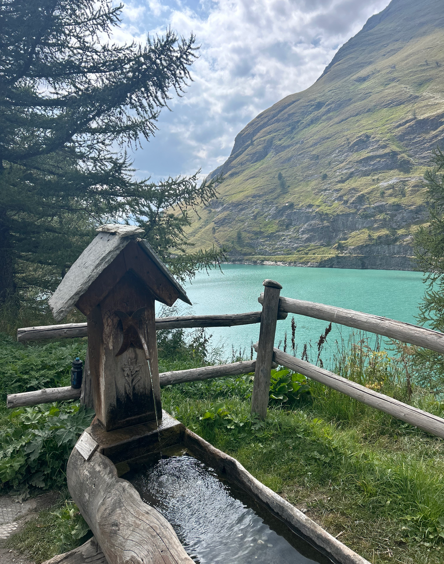 Fontaine en bois près d'un lac turquoise de montagne