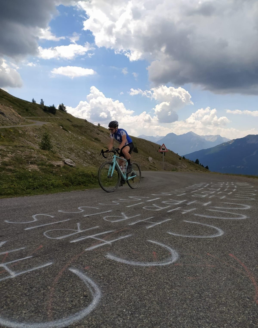 Cycliste sur route de montagne sous ciel nuageux
